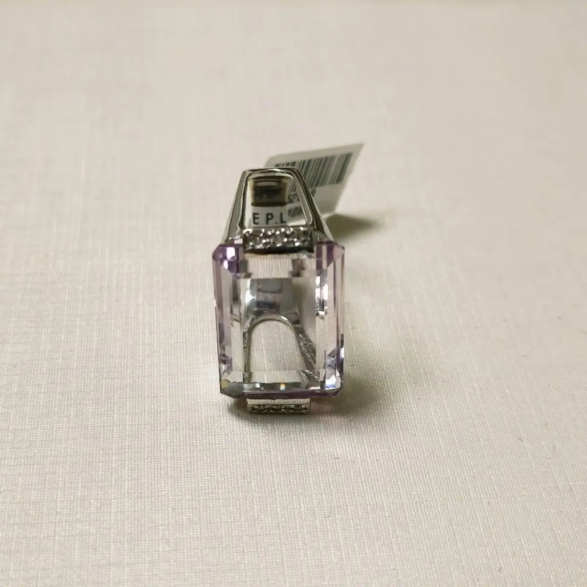 LOTE 002 - Um anel, em ouro branco, com uma pedra de quartzo lilás, retangular, seis pedras de diamantes nas laterais