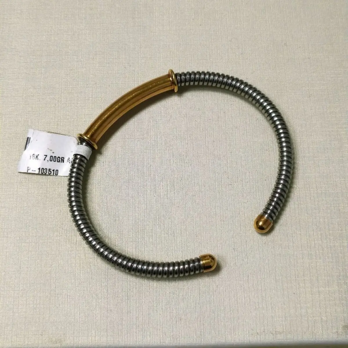 LOTE 003 - Uma pulseira, estilo cabo, com as ponteiras, adereço central em ouro amarelo