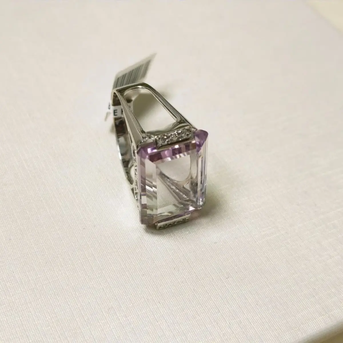 LOTE 002 - Um anel, em ouro branco, com uma pedra de quartzo lilás, retangular, seis pedras de diamantes nas laterais