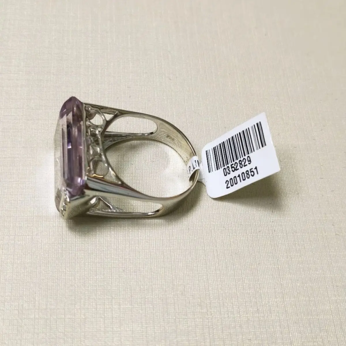 LOTE 002 - Um anel, em ouro branco, com uma pedra de quartzo lilás, retangular, seis pedras de diamantes nas laterais