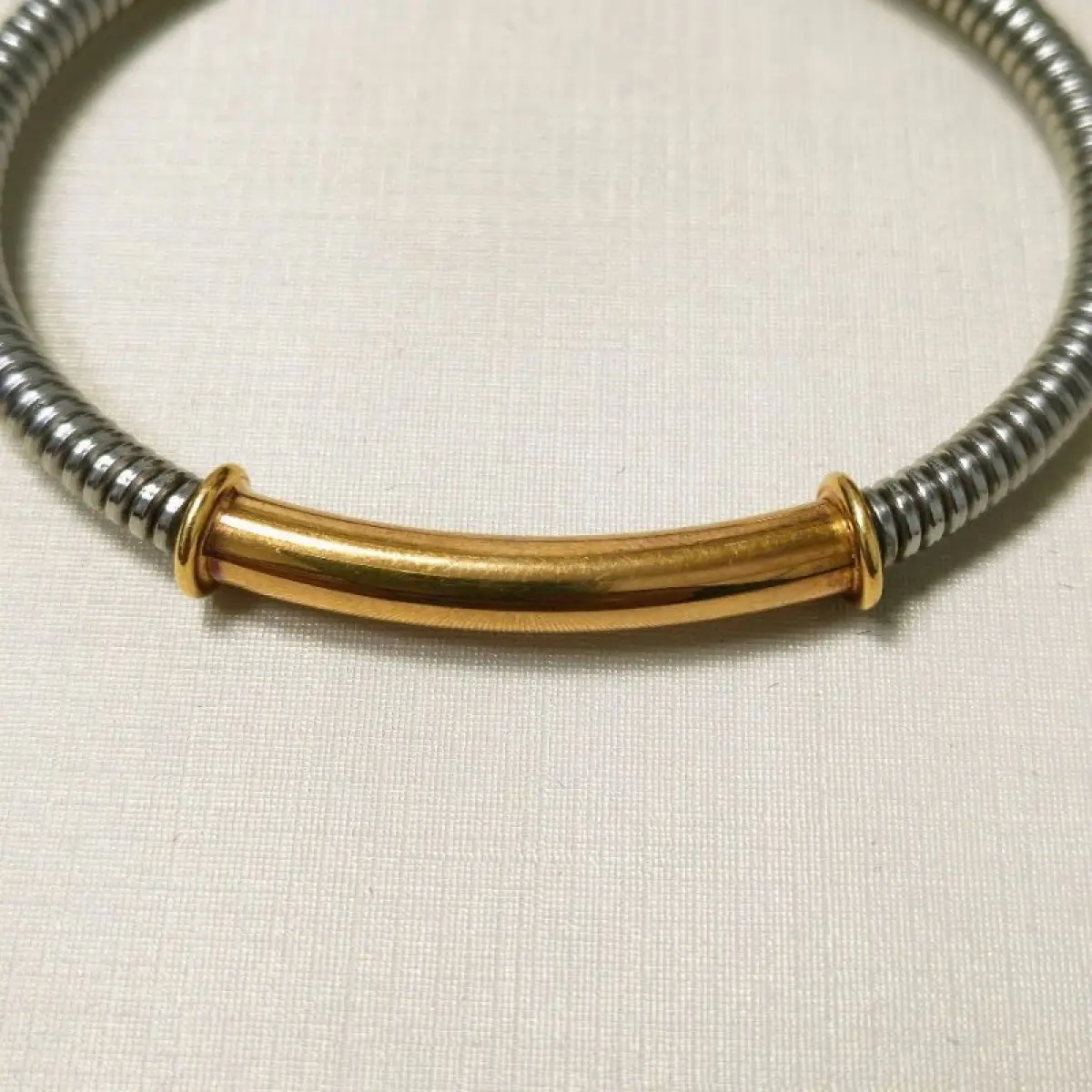 LOTE 003 - Uma pulseira, estilo cabo, com as ponteiras, adereço central em ouro amarelo