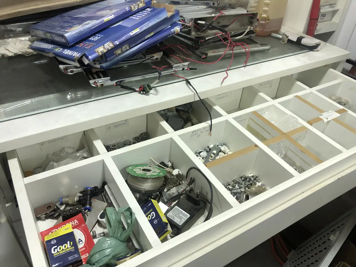 LOTE 046 - Lote com guilhotina, esmerilhadeiras, serras, parafusos, banquetas, manequim, catalogos, cortinas, fitas de borda, serra circular, lixadeiras, engraxadeira, cones, cintas, catracas, vaso, cintos alpinista, prateleira, balcão, armarios, silicones, soprador de calor, etc 