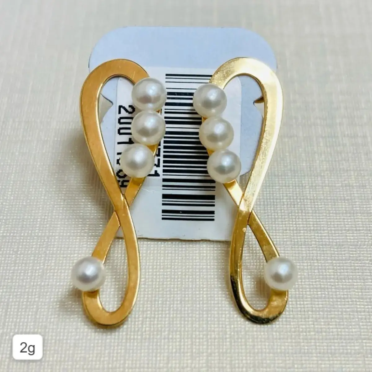 LOTE 007 - Par de brincos: Modelo formato infinito com oito pérolas, tarracha borboleta. Ouro 18k. Código: 957771