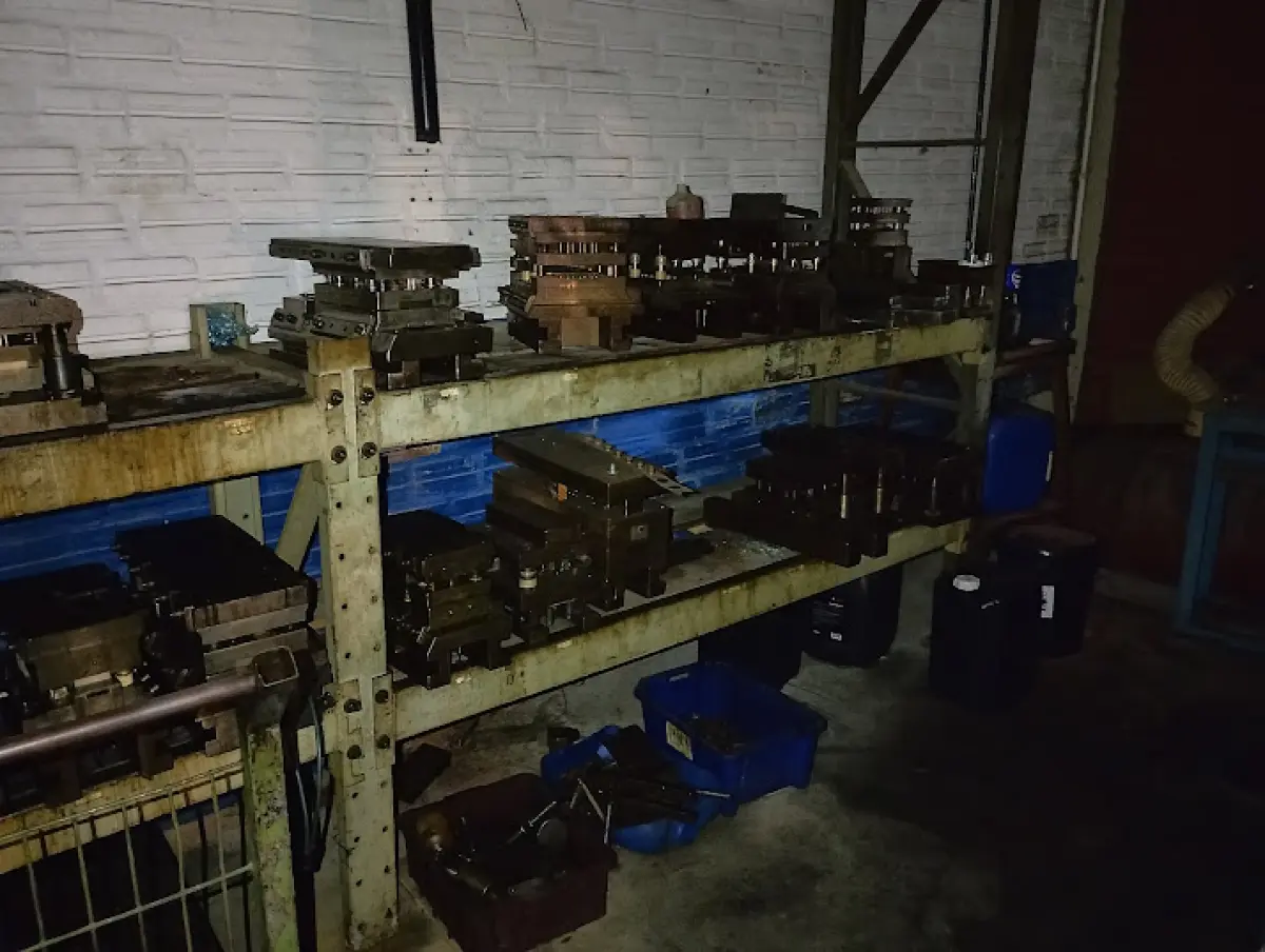 LOTE 176 - Lote composto por dezenas de moldes e matrizes metálicas industriais (corte, repuxo e estamparia) de variados tamanhos e formatos; estruturas e estantes de aço industriais para armazenagem; 01 carrinho manual de movimentação de carga; e conjunto de componentes de ferramentaria soltos sobre bancada (pinos guia, molas de compressão, punções e blocos de aço).