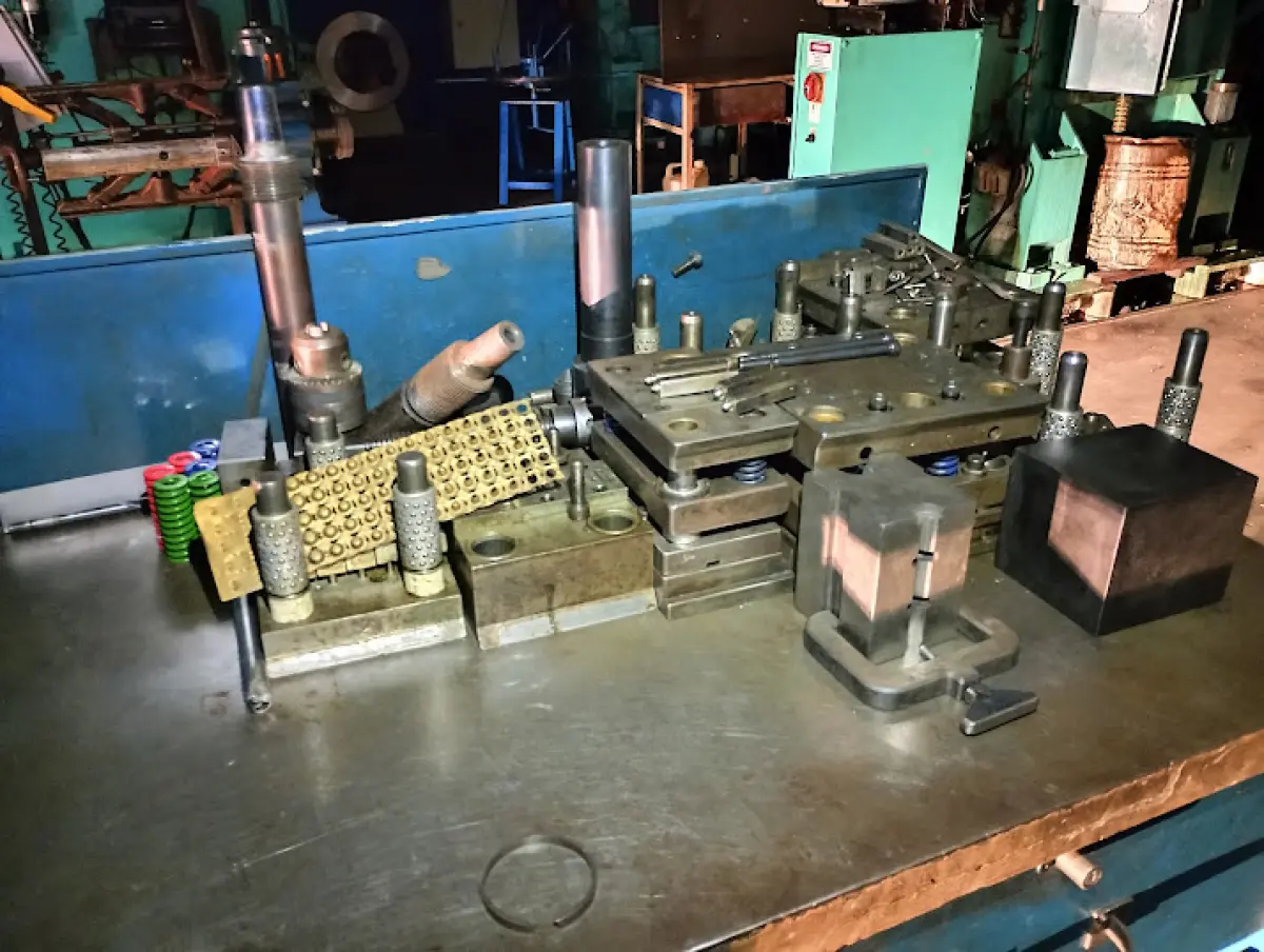 LOTE 176 - Lote composto por dezenas de moldes e matrizes metálicas industriais (corte, repuxo e estamparia) de variados tamanhos e formatos; estruturas e estantes de aço industriais para armazenagem; 01 carrinho manual de movimentação de carga; e conjunto de componentes de ferramentaria soltos sobre bancada (pinos guia, molas de compressão, punções e blocos de aço).