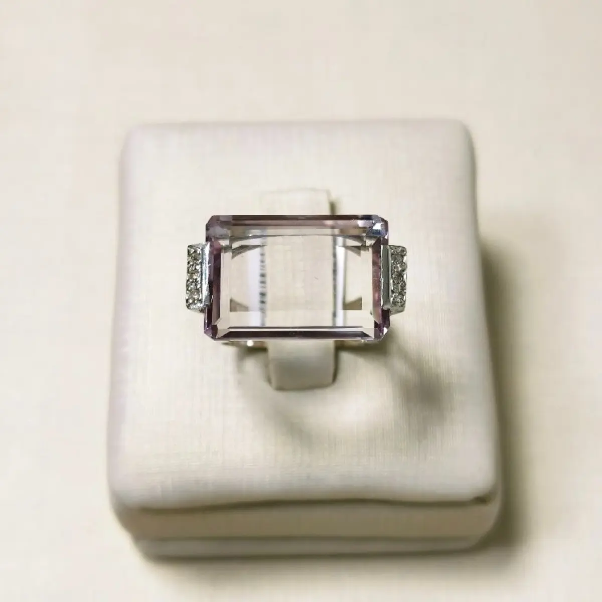 LOTE 002 - Um anel, em ouro branco, com uma pedra de quartzo lilás, retangular, seis pedras de diamantes nas laterais