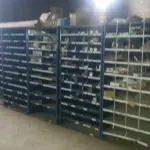 LOTE 5 - Lote de prateleiras metálicas com peças de reposição para veículos, peças de manutenção, partes de carro, tais como: para-choques, capôs de carro, correias, parafusos, porcas, tapetes de carro, painéis plásticos, aros de rodas pneus, partes de lataria de carros, lanternas, etc, aval.: R$ 55.000,00