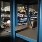 LOTE 5 - Lote de prateleiras metálicas com peças de reposição para veículos, peças de manutenção, partes de carro, tais como: para-choques, capôs de carro, correias, parafusos, porcas, tapetes de carro, painéis plásticos, aros de rodas pneus, partes de lataria de carros, lanternas, etc, aval.: R$ 55.000,00