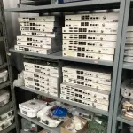 LOTE 348 - Armario 2 portas, prateleira com placas, mesa com bancada, prateleira com antenas, rack de equipamentos de teste, roteadores, carrinhos 