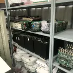 LOTE 348 - Armario 2 portas, prateleira com placas, mesa com bancada, prateleira com antenas, rack de equipamentos de teste, roteadores, carrinhos 