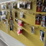 LOTE 042 - Lote com quador mostruario, silicone, linhas de nylon, serrote, martelo, disco de corte, pedra para retificas, regua, tesourão, mostra de modelos de parafusos, pedras de afiar, tampa de vaso, adaptador de mangueira, torneiras, trincha, rolo de pintura, capacetes de epi, oculos. 