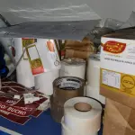 LOTE 222 - LOTE DE BOBINAS DE ETIQUETAS, SACOS PLÁSTICOS, FITAS ADESIVAS, TOUCAS PLÁSTICAS DESCARTÁVEIS, ETC.; SACOLAS DE PLÁSTICO E DE PAPEL COM A LOGOMARCA ARMAZEM DA CARNE